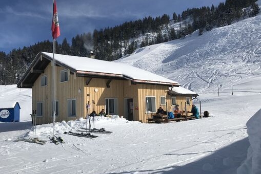 Die Naturfreunde Hütte in hellem Braun im Winter.