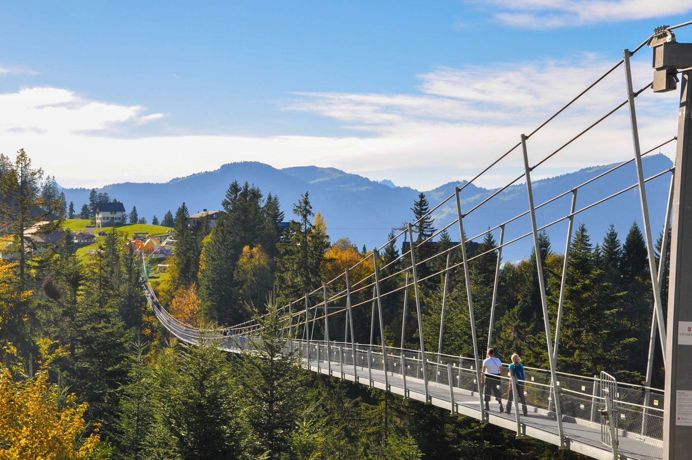 Die Hängebrücke an einem schönen Herbsttag. Zwei Wanderer passieren die Brücke Richtung Mostelberg