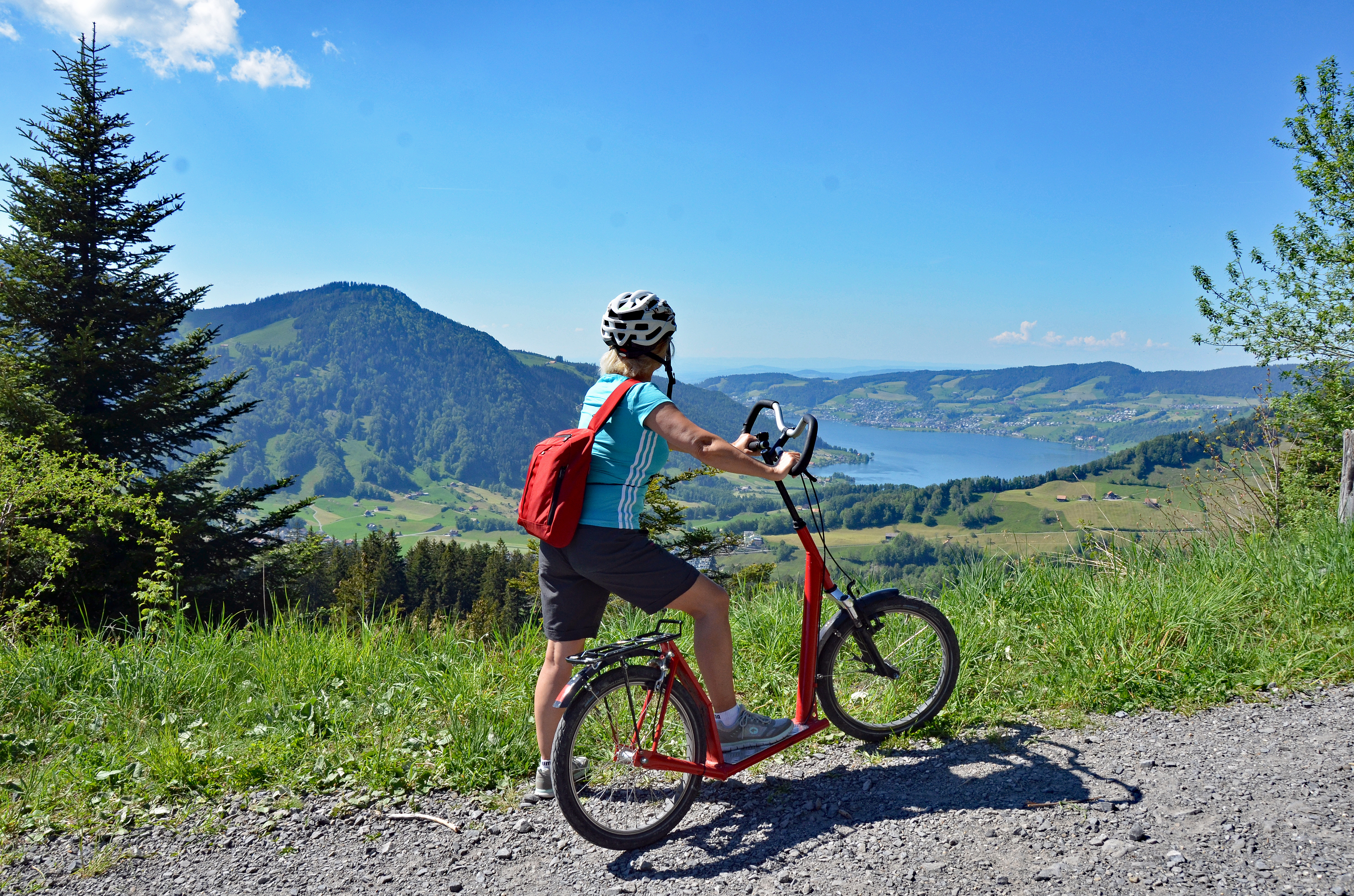 Eine Frau auf dem Trotti mit Blick auf den Ägerisee. 
